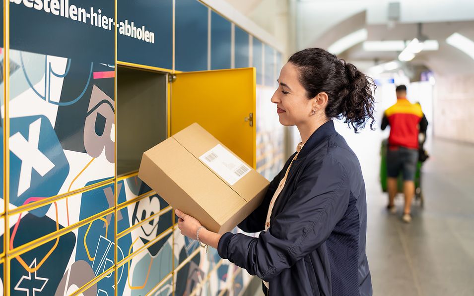 Frau zieht ein Paket aus einer Abholstation