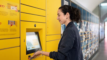 Frau scannt einen Code auf dem Handy vor der Abholsbox